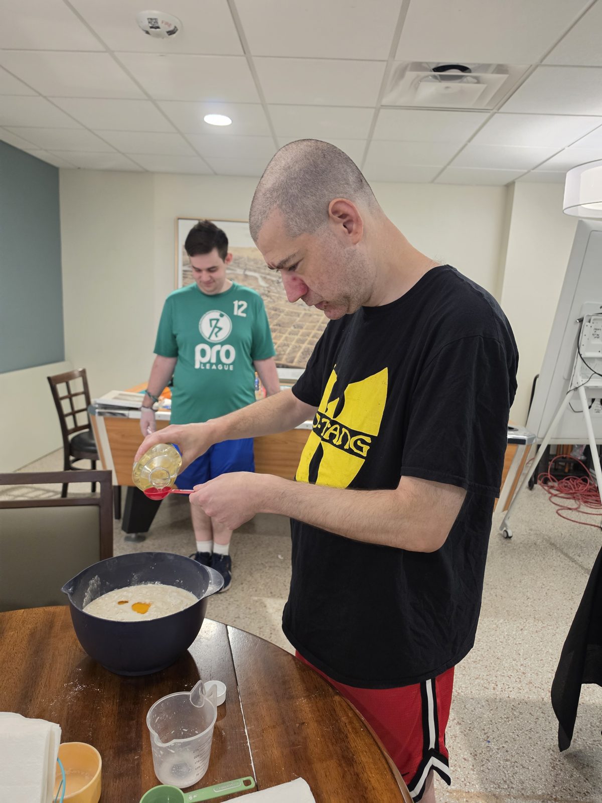 CAI participants add ingredients to a mixing bowl during a pancake cooking activity.