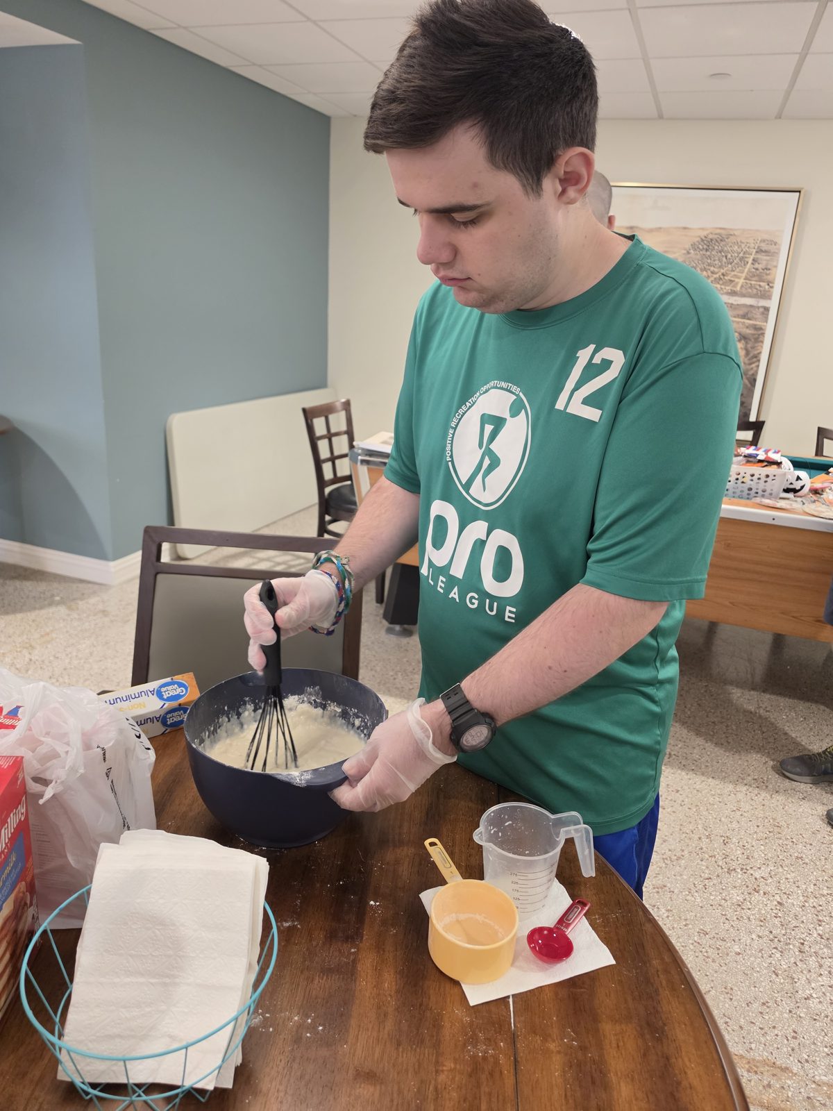 A CAI participant whisks pancake batter in a mixing bowl.